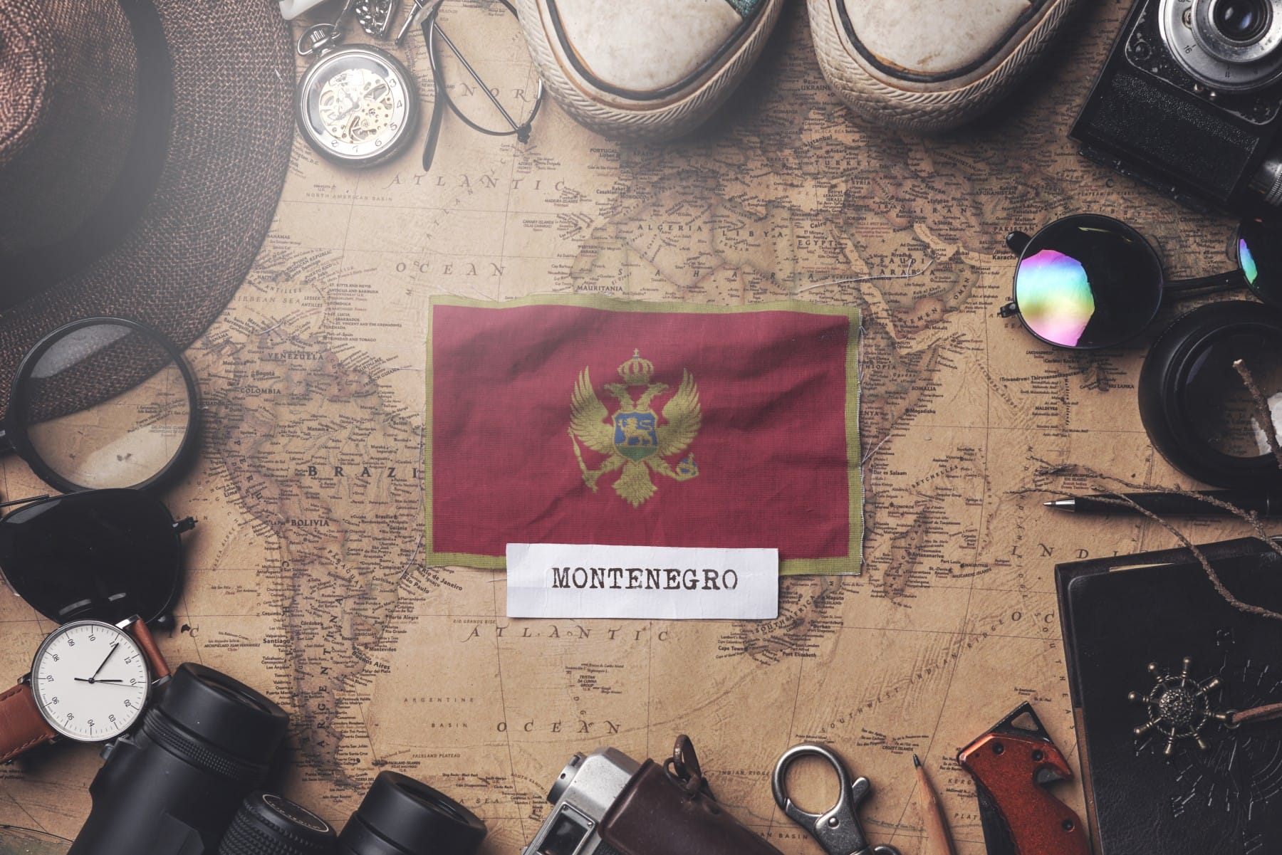Montenegrin flag between traveler's accessories on old vintage map