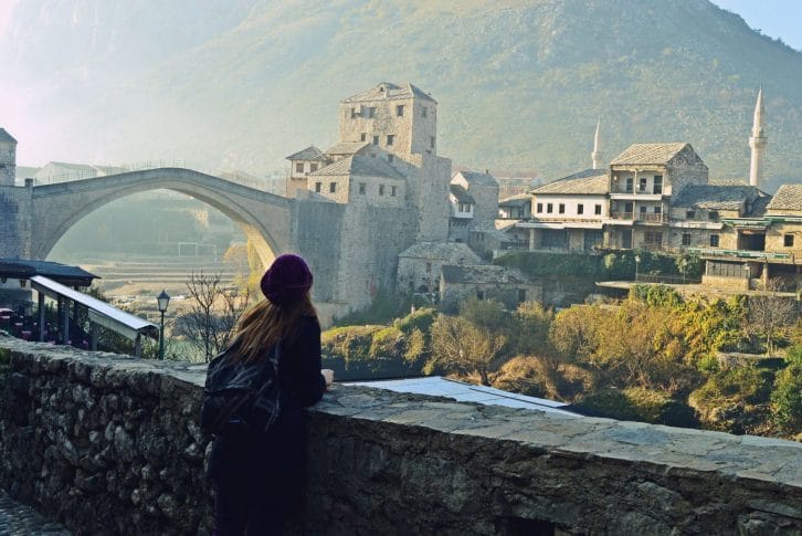 Girl with rucksack look at old bridge in mostar bosnia and herzegovina