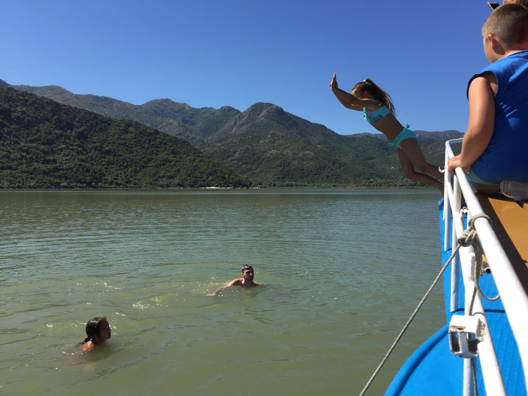 The girl is jumping in the water from the boat, Skadar Lake
