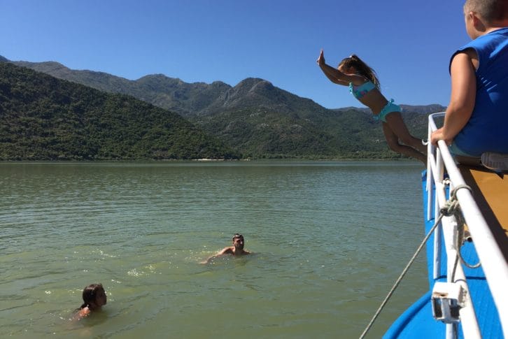 The girl is jumping in the water from the boat, Skadar Lake
