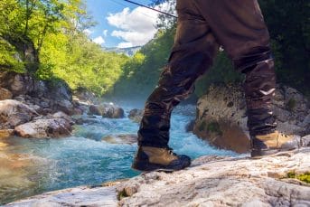 A fisherman standing on a rock by the river