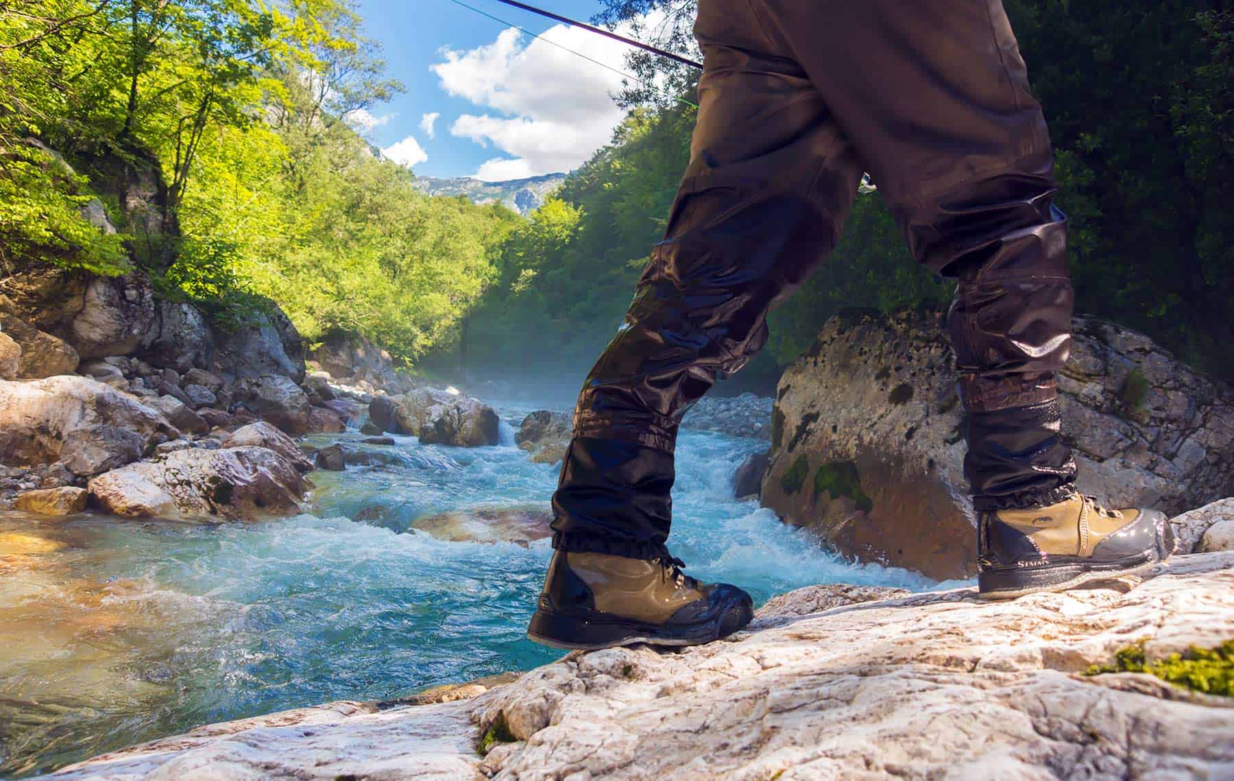 A fisherman standing on a rock by the river