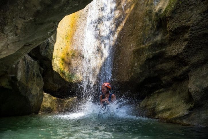 Girl jumping down in freezing water on canyoning at Rikovac
