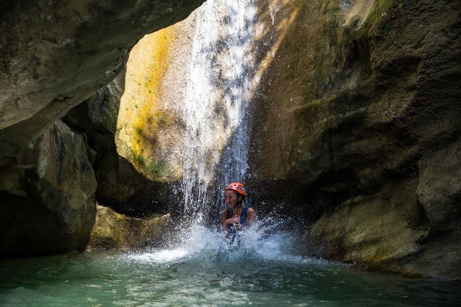 Girl jumping down in freezing water on canyoning at Rikovac