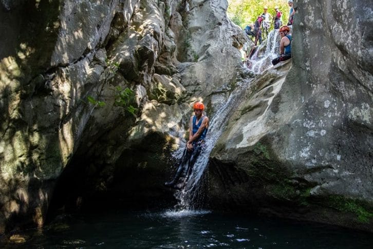 Group sliding down tiny waterfall during canyoning in Rikovac