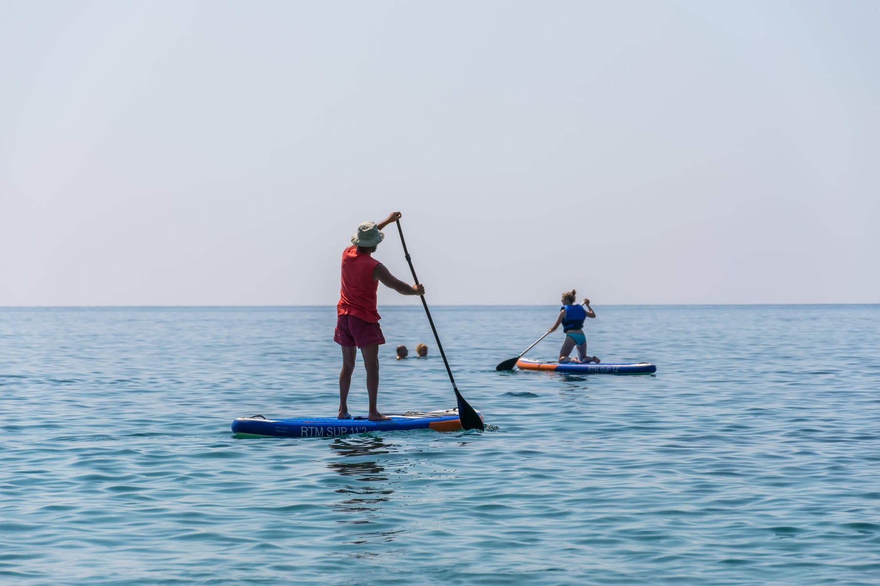 Tourists are engaged in rowing on the board (sup) on the surface of the calm sea 2