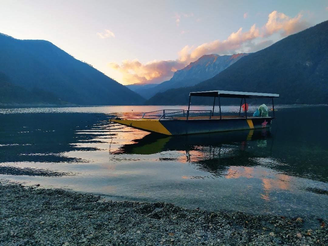 A boat on Piva Lake at sunset