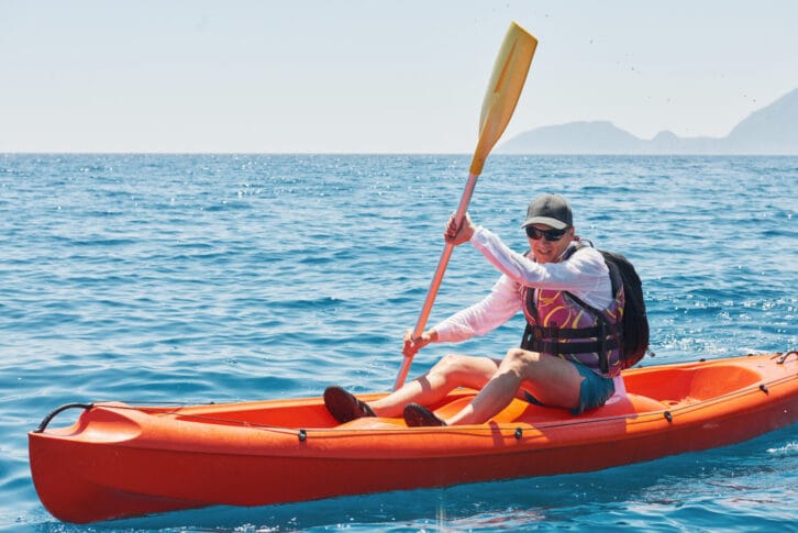 Boat kayaking near cliffs on a sunny day.