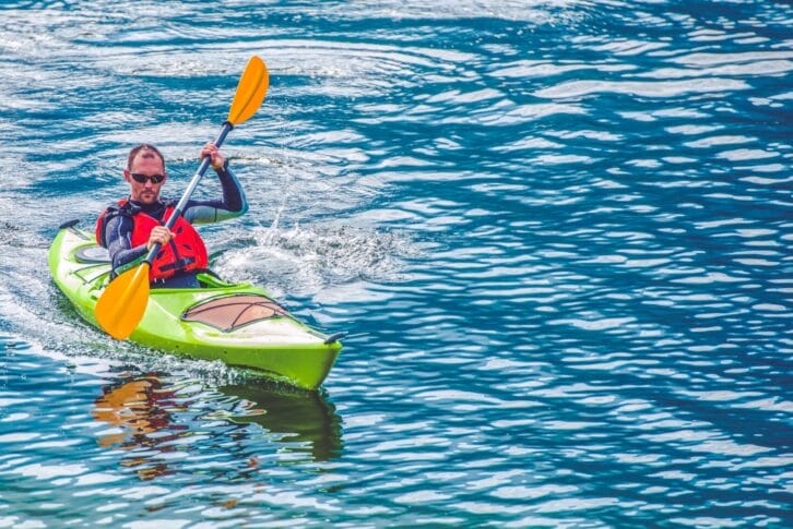 Kayak Tour. Caucasian Men Paddling in the Kayak on the Lake.