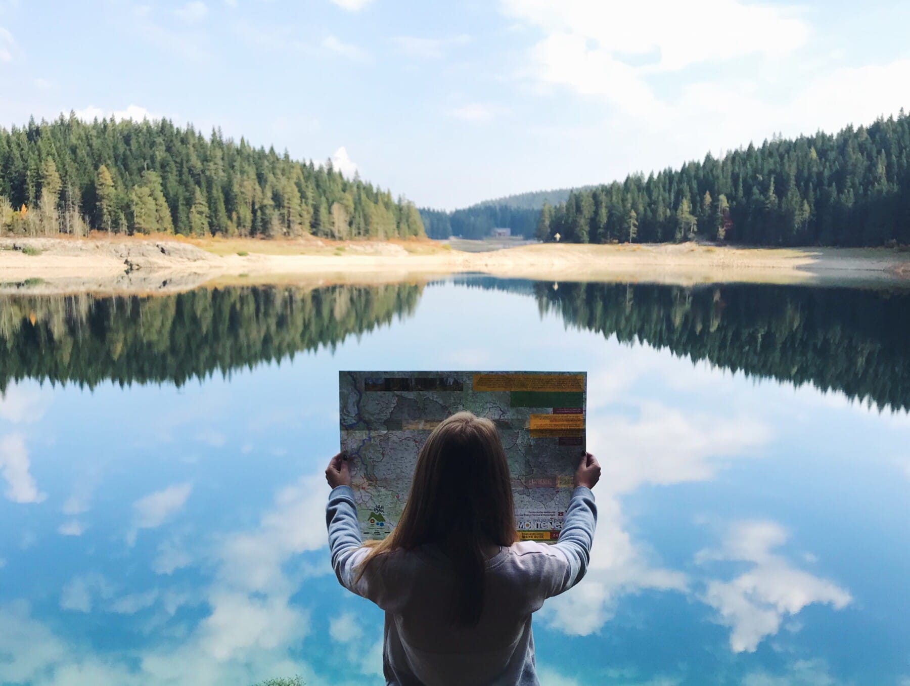 Girl with hiking map surrounded by lake and forest, Black Lake