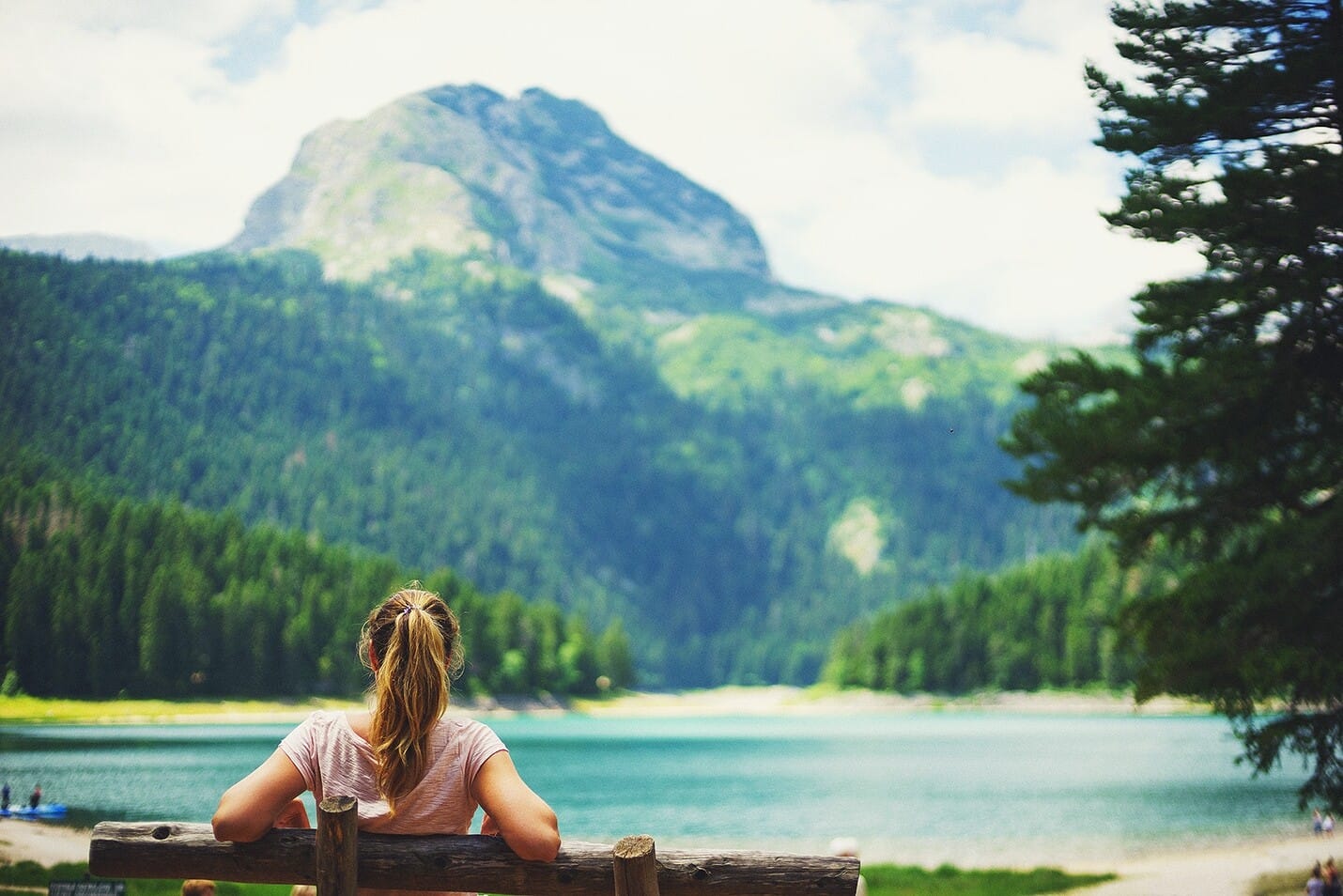 Girl sitting on the wooden bench nearby the Black lake in NP Durmitor Montenegro