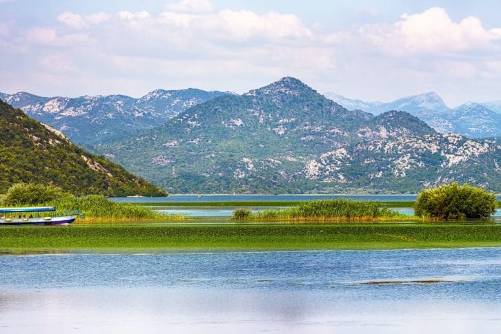 Awesome view of Skadar lake surrounded by green mountain peaks on a sunny day.