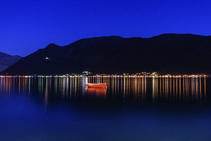 View towards harbour and town of Perast in the Bay of Kotor, Montenegro at night, fishing boat