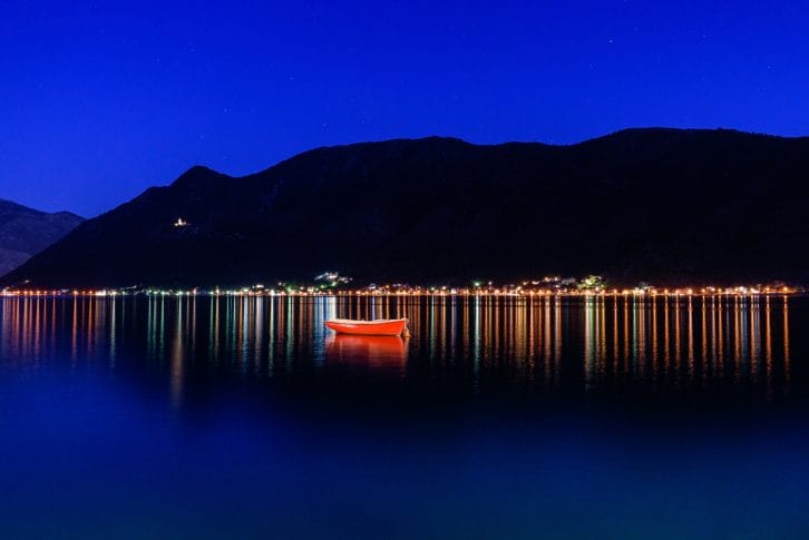View towards harbour and town of Perast in the Bay of Kotor, Montenegro at night, fishing boat